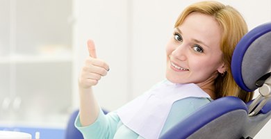 Smiling woman in dental chair giving thumbs up