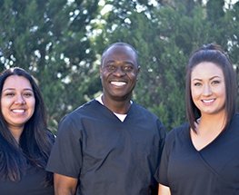 Smiling woman in dental chair talking to team member