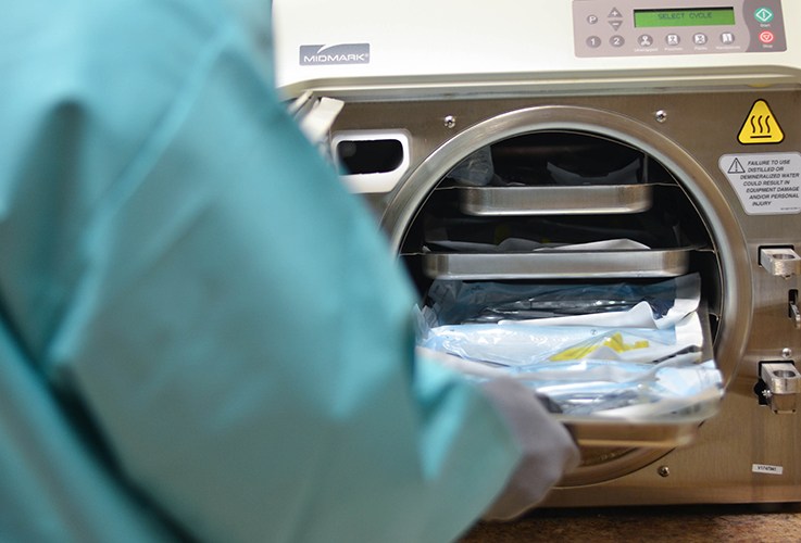 Employee placing dental instruments in sterilizer