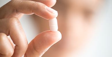 Hand holding white tablet pill